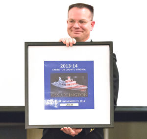 U.S. Navy Lt. Cmdr. Darren Nelson holds the 2013 Arlington County decal, which highlights the USS Arlington. Nelson will be the first commander of the Arlington upon its commissioning in April. Washington-Lee High School student Ben Jenks designed the decal. (Photo by Deb Kolt)