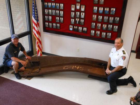 Eagle Firefighters Association president Aaron Weisenberger and Dover Air Force Base Deputy Fire Chief Rodney Coleman kneel next to two support beams from Tower One of the World Trade Center. These beams will be part of a 9/11 memorial being built at the Air Mobility Command Museum in Dover. (Delaware State News/Chris Flood)