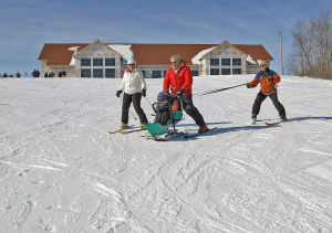 Gary Nelson, center, controls a bi-ski carrying a boy on the slope in front of Annie's House, the new chalet and adaptive skiing center named for his daughter, Ann Nicole Nelson. At left is Sherry McCabe and at right is Frank LaQua.