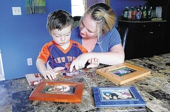  Jennifer Feely-Artola looks over family photographs of her father Tuesday with her son Justin in her Mount Hope home. Her father Frank Feely was killed in the September 11, 2001, terror attacks. Chet Gordon,Times Herald-Record