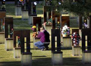 A woman places flowers and a stuffed animal on a chair before the start of the 19th anniversary Remembrance Ceremony at the Oklahoma City National Memorial Saturday morning, April 19, 2014, to honor the memory of the 168 victims killed in the 1995 bombing of the Murrah Federal Building. Photo by Jim Beckel, The Oklahoman