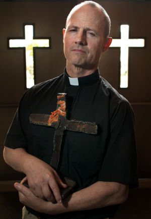 Rev. Patrick Malone, in a 2011 photo, holds a cross cut from a girder at Ground Zero. Matt Miller, The World-Herald