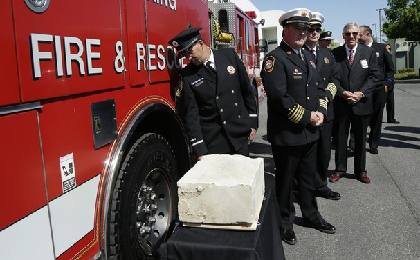 South King Co. Fire and Rescue officials, including assistant chief Gordon Olson, second from left, stand Monday, May 12, 2014, next to a piece of limestone that was part of the building at the Pentagon. (AP photo)