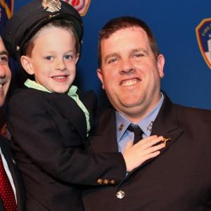 BRAVEST FAMILY: Newly promoted Lt. Peter J. Ganci III, whose dad, FDNY Chief of Department Peter Ganci, died on 9/11, holds son Peter IV yesterday at the ceremony.