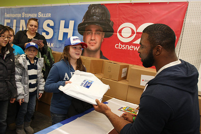 Jordan Mooney , PS 38 5th grader receives her bag of school supplies from Justin Tuck. Justin Tuck, Giants football player visits Siller Foundation Relief Center and donates books and school supplies along side United Way and MTV. (Staten Island Advance/Jan Somma-Hammel)