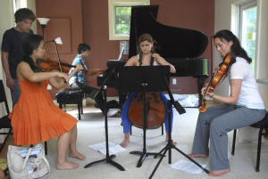Musicians (from left) Manami Mizumoto, 17, of New York, N.Y., Nicholas Mendez, 14, of Los Angeles, Calif., Madeleine Bouissou, 17, of Ridgefield, Conn. and Ellen Shrock, 19, of Setauket, N.Y. take direction from Yellow Barn faculty member and artistic director, Seth Knopp of Baltimore, MD. while rehearsing a piece of music written by Phillip Golub, 20, of Los Angeles, Calif. (©Kayla Rice)