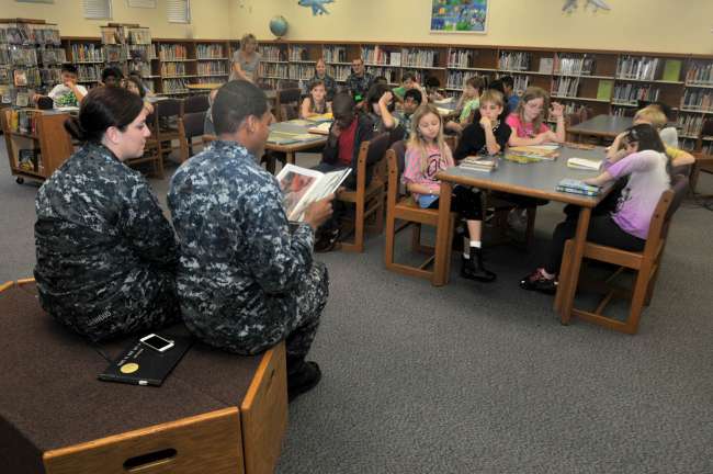 Hospital Corpsman Danielle Tannous and Hospital Corpsman 2nd Class Thionta Buckner from amphibious transport dock ship USS New York (LPD 21) reads to a group of students at the Jacksonville Beach Elementary (JBE) School Invention Convention. Photo by MC3 Angus Beckles