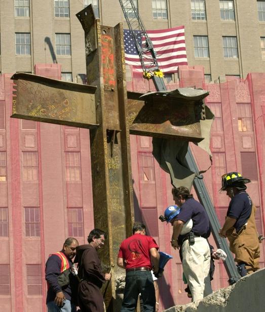Father Brian Jordan (2L) blesses, October 4, 2001, a cross of steel beams found amidst the rubble of the World Trade Center by a laborer two days after the collapse of the twin towers. Reuters