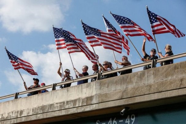 Betty Farrington, third from left, husbandís flag during the dedication of the Leonard A. Farrington 9/11 Memorial Bridge on Sutton Road and I-77 Sunday, September 8. 2013. Farrington, a World War II Navy veteran, waved the flag from the overpass on September 11 after the 2001 attacks in New York and Washington Farrington died in 2012 at age 89. The state recently renamed the bridge the "Leonard A. Farrington 9/11 Memorial Bridge." (AP Photo/The Herald, Jeff Sochko)