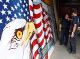 Jimmy Flynn of the Lawrence Fire Department and Firefighter Timmy Boutin look at the 9-11 mural that was restored this summer, Photo Amy Sweeney