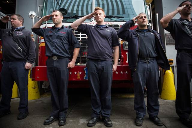 Firefighters stand at attention Saturday as emergency vehicles transporting the unidentified remains of victims of the 9/11 attack to the new World Trade Center site, where they will be kept beneath the museum. Andrew Burton/Getty Images